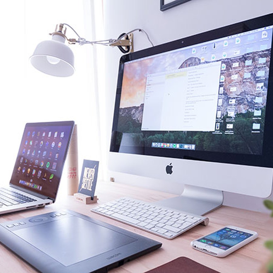 A desktop, laptop, tablet and phone on one desk